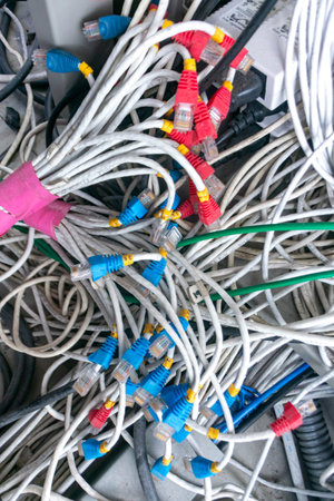 A close-up view of tangled network cables showcasing vibrant connectors in a chaotic arrangement,...