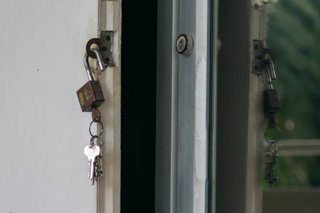 A close-up image featuring a padlock and keys attached to an interior door. The photograph highlights security features and household safety elements.の写真素材