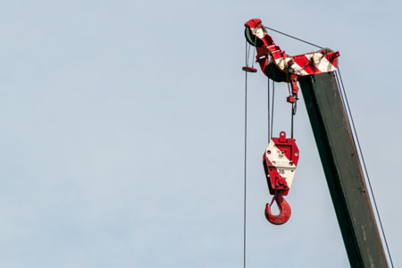 A bright red hook on a construction crane arm against a clear sky. This image captures the essence of industrial machinery in action, showcasing its strength and purpose.の写真素材