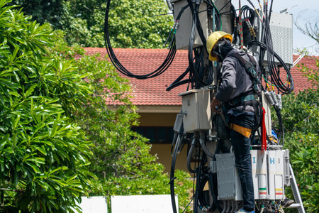 A technician performs maintenance on an elevated platform amidst greenery, showcasing the importance of safety and expertise in utility work.の写真素材
