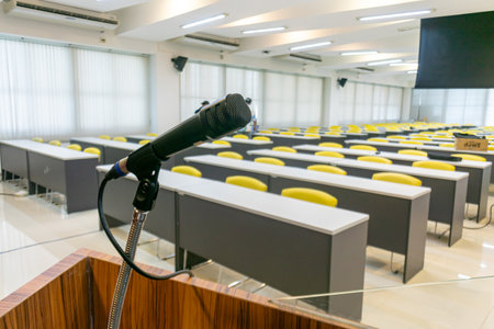 A modern classroom featuring a podium and microphone setup, designed for presentations and lectures, showcasing an empty learning environment with bright furniture.の写真素材