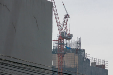 A construction site featuring a tall crane and scaffolding against a cloudy sky, highlighting urban development and modern architecture practices.の写真素材