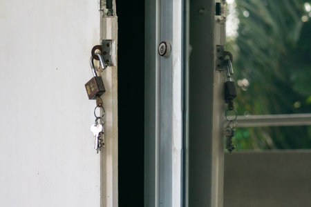 Close-up view of an open door featuring keys and a padlock, highlighting security elements and interior design aspects in a natural setting.の写真素材