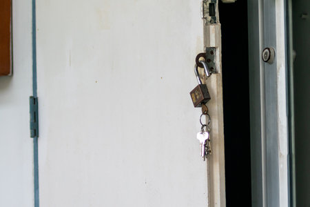 A close-up of an open door with a padlock and keys hanging from the handle. This image symbolizes security, access, and new beginnings in a residential environment.の写真素材