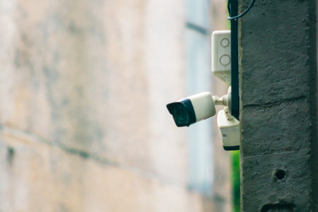 A security camera mounted on a concrete wall captures surveillance footage. This image represents...