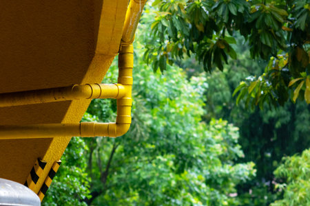 A vibrant scene featuring bright yellow pipes contrasted against lush green foliage. This image...