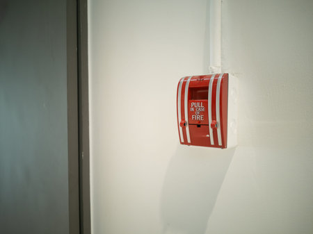 Red fire alarm pull station mounted on a wall, designed for emergency response in public spaces....