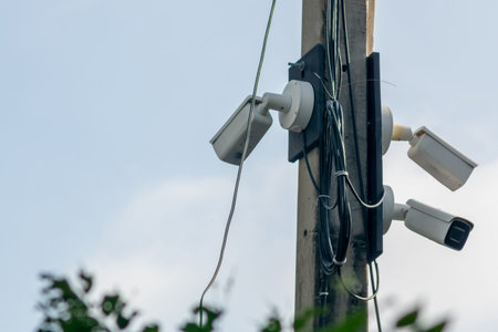 This image showcases a set of security cameras mounted on a utility pole, surrounded by nature. The...