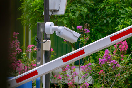 Security camera positioned at an entrance, surrounded by colorful flowers and greenery. The image captures the harmony between technology and nature in a tranquil setting.の写真素材