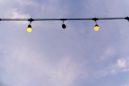 A charming view of decorative string lights gracefully hanging above a vibrant blue sky, evoking a warm and inviting atmosphere. Perfect for leisure or festive themes.の写真素材