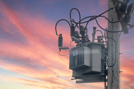 A close-up view of an electrical transformer mounted on a utility pole. The intricate arrangement of wires and cables showcases power distribution technology in an urban setting.の写真素材