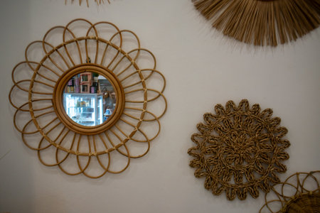 This image showcases a beautifully crafted rattan mirror surrounded by intricate wall art, perfectly blending natural textures and aesthetics for stylish home decor.の写真素材