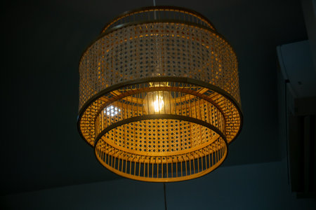 This elegant hanging lamp features a unique rattan design, providing warm illumination and enhancing any interior space with its artistic presence.の写真素材