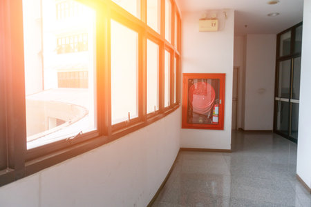 A bright and modern hallway featuring fire safety equipment. The space is well-lit, showcasing the importance of safety and emergency preparedness in buildings.の写真素材