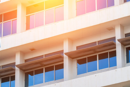 A modern building features an engaging facade with sleek glass windows and distinct architectural lines, reflecting sunlight and urban sophistication.の写真素材