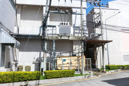A detailed view of an urban utility structure showcasing power lines and electrical equipment, set against a clear blue sky in a city environment.の写真素材