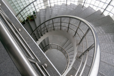 A captivating view of an elegant spiral staircase showcasing a blend of modern design and metal railing, ideal for architectural and interior themes.の写真素材