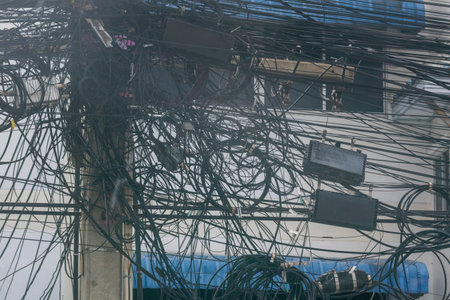 A chaotic display of tangled wires and cables on a utility pole showcases the complexity of urban infrastructure and the vital connections of modern life.の写真素材