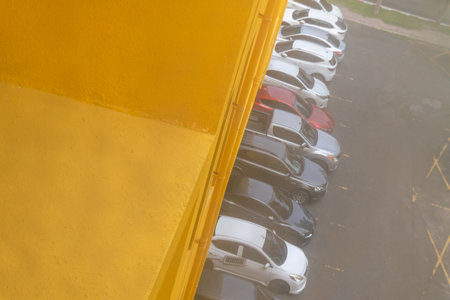 Aerial view of a parking lot filled with various parked cars in different colors, showcasing urban design and organized vehicle patterns on a sunny day.の写真素材