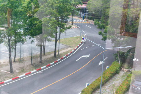 A winding road surrounded by lush trees and greenery, showcasing urban infrastructure in a serene setting. Ideal for themes of travel and nature.の写真素材