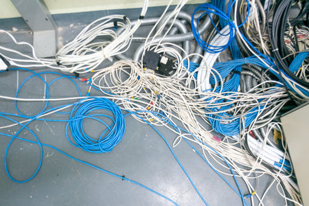 A chaotic scene showcasing a mix of tangled wires and cables on a floor surface, illustrating the...