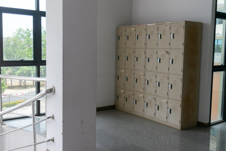 Bright and spacious locker room featuring metal lockers and large windows. Perfect for schools, gyms, or workplaces requiring organized storage solutions.の写真素材