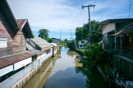 A serene canal scene featuring traditional wooden houses lining the waterway under a clear blue sky, capturing the essence of coastal living and community atmosphere.の写真素材