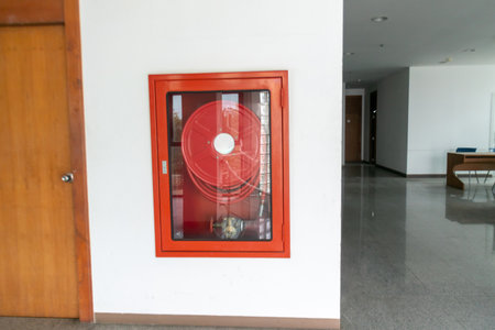 A bright red fire safety equipment cabinet mounted on a wall in a modern interior building, emphasizing accessibility and readiness for emergency situations.の写真素材