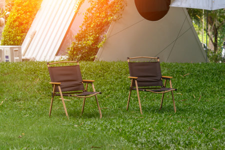 Two stylish outdoor chairs on green grass invite relaxation in a peaceful garden setting, perfect for summer picnics or leisure activities in nature.の写真素材