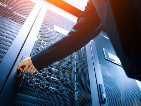 A business professional reaches for a server cabinet in a modern data center, highlighting the...