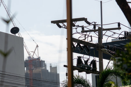 A construction site showcasing a crane and power lines under a clear blue sky. The image captures urban development and industrial progress in motion.の写真素材