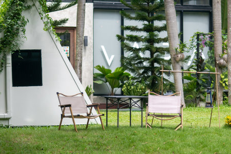 A serene outdoor scene featuring stylish seating and a table surrounded by lush greenery, perfect for relaxation and enjoying nature's beauty.の写真素材