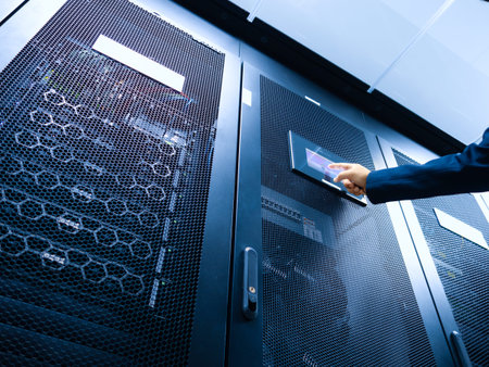 A professional hand reaches for a control panel on a server rack, illustrating technology and...