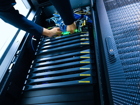A technician works meticulously inside a server rack, connecting cables and ensuring optimal operation of network hardware in a modern data center environment.の写真素材