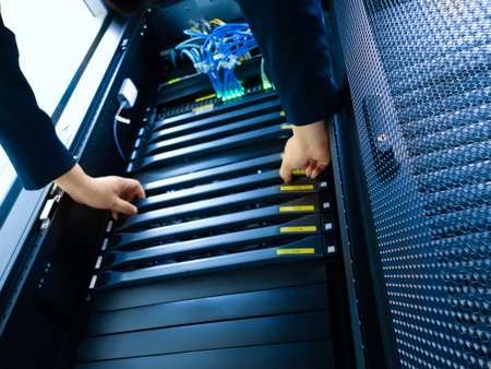 A close-up view of hands handling equipment within a server rack. This setup highlights the...