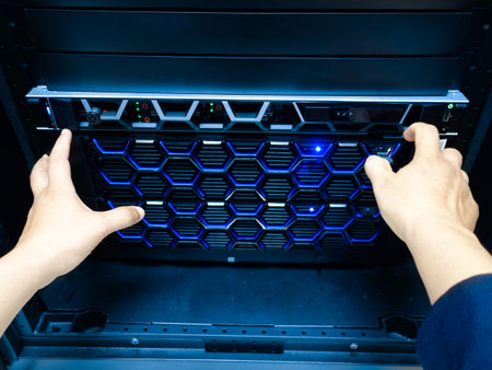 A technician's hands operate a modern server unit featuring blue LED lights. The image captures the intricacies of technology in a professional IT environment.の写真素材