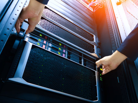 A technician is installing a server into a data center rack, showcasing the intricate technology and hardware necessary for modern computing environments.の写真素材