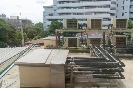 This image features a rooftop view showing air conditioning units along with pipes in an urban setting, highlighting modern HVAC technology and infrastructure.の写真素材