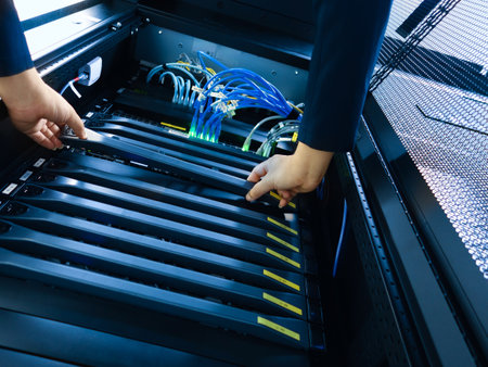 A technician performs maintenance on a server rack, managing cables and ensuring proper connectivity for optimal performance in a data center environment.の写真素材