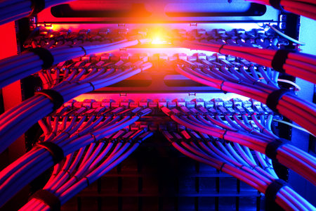 A vibrant view of network cables in a server rack displays a striking mix of blue and red lights,...