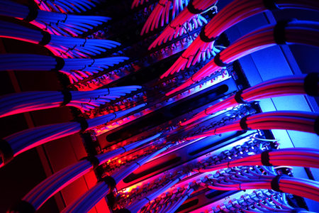 A vibrant view of network cables illuminated by colorful lighting in a modern data center. This...