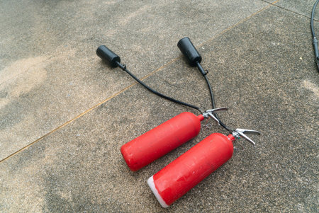 Two red fire extinguishers resting on a concrete surface, showcasing essential safety equipment for...
