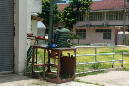 This image depicts a green water tank positioned next to a building exterior, showcasing elements of...