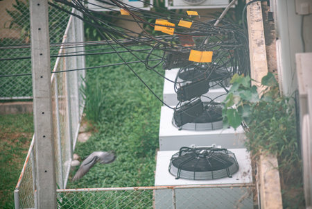 An aerial view of air conditioning units surrounded by tangled wires, showcasing urban...