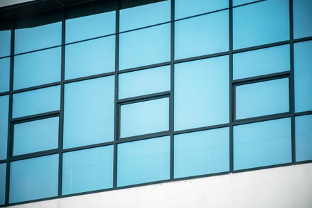 Close-up view of a modern building facade featuring a geometric arrangement of glass windows that...