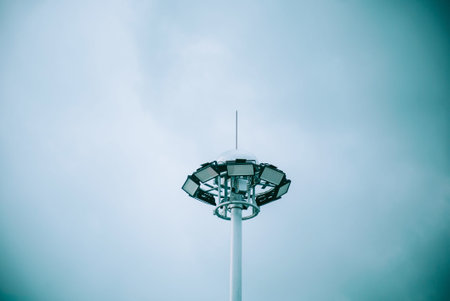 A detailed view of a modern light pole against a cloudy sky. The design highlights urban functionality and technology, showcasing contemporary outdoor lighting solutions.の写真素材