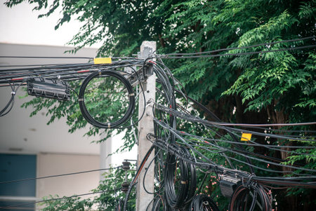An urban utility pole showcases an intricate arrangement of power wires, blending technology and...