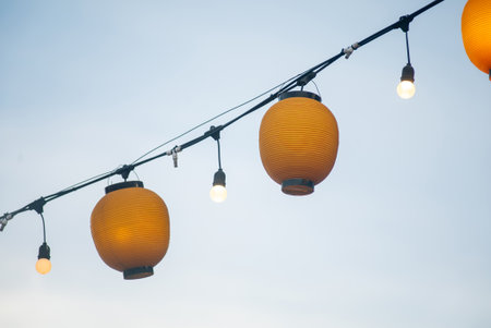 Colorful lanterns hang beautifully against the evening sky, creating a warm and inviting atmosphere perfect for outdoor celebrations and gatherings.の写真素材