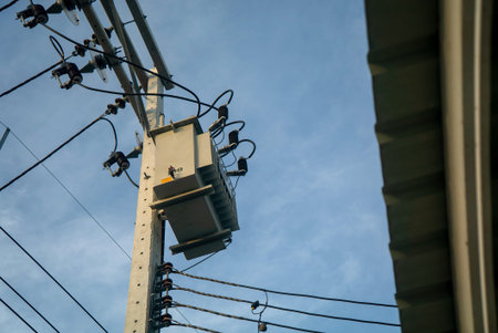 Image showcases a power transformer mounted on a utility pole, with electrical wires interwoven...