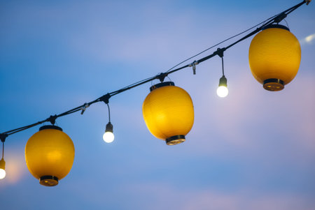 Bright yellow lanterns hang gracefully against a soft blue sky, creating a captivating atmosphere...